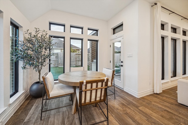 dining area featuring dark wood-type flooring and vaulted ceiling