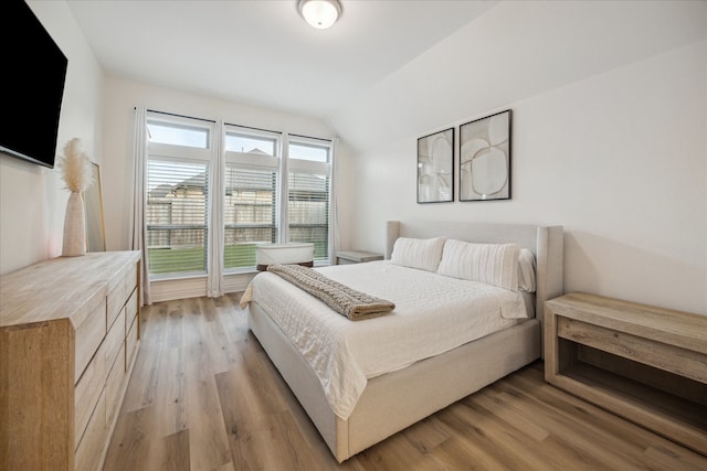 bedroom with light hardwood / wood-style floors and vaulted ceiling