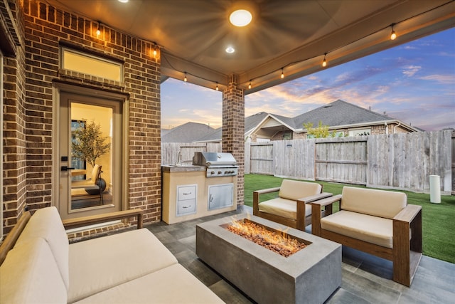 patio terrace at dusk with an outdoor kitchen, an outdoor fire pit, and a grill