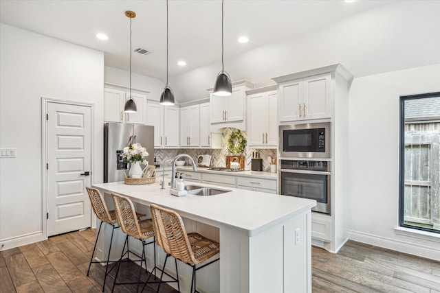 kitchen with hanging light fixtures, sink, appliances with stainless steel finishes, and hardwood / wood-style floors