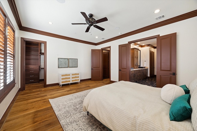 bedroom with a walk in closet, crown molding, dark hardwood / wood-style floors, ceiling fan, and a closet