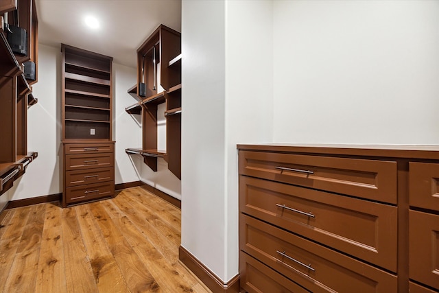 walk in closet with light hardwood / wood-style floors