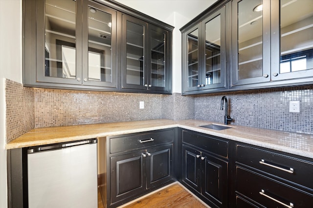 kitchen featuring tasteful backsplash, dishwasher, sink, and light hardwood / wood-style floors