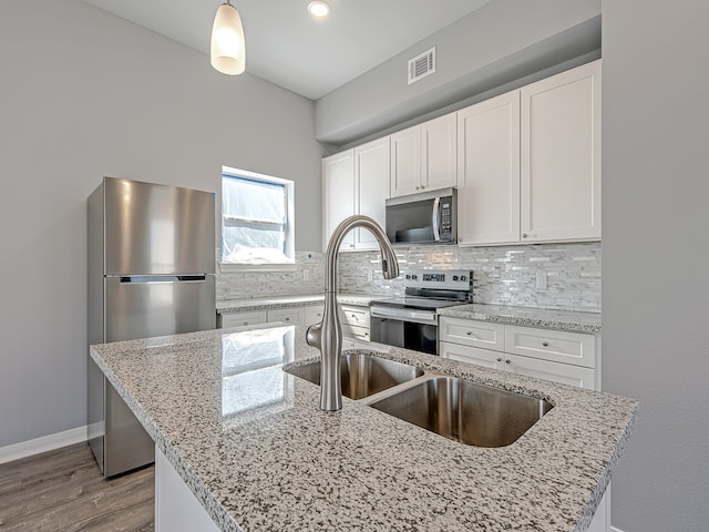 kitchen featuring pendant lighting, appliances with stainless steel finishes, white cabinets, and light stone counters