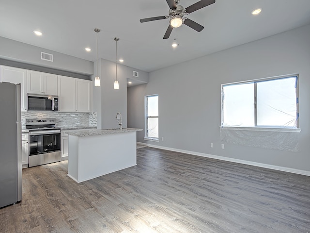 kitchen featuring stainless steel appliances, white cabinets, hardwood / wood-style floors, light stone countertops, and decorative light fixtures