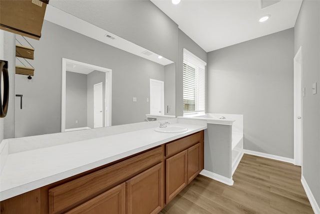 bathroom featuring hardwood / wood-style flooring, a tub to relax in, and vanity