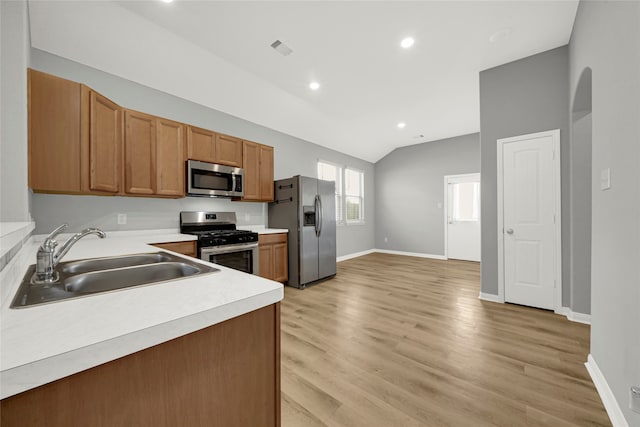 kitchen featuring lofted ceiling, sink, light wood-type flooring, and appliances with stainless steel finishes