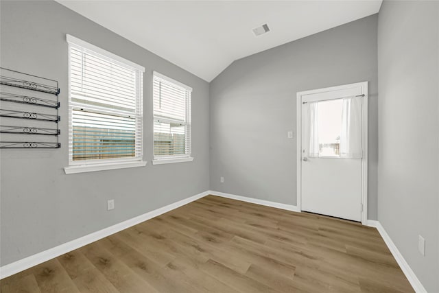 unfurnished room featuring light hardwood / wood-style flooring and lofted ceiling