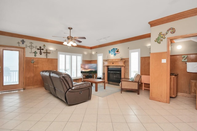 living room featuring ornamental molding, wooden walls, ceiling fan, and light tile patterned flooring