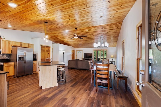 kitchen featuring vaulted ceiling, dark hardwood / wood-style floors, light brown cabinets, appliances with stainless steel finishes, and decorative light fixtures