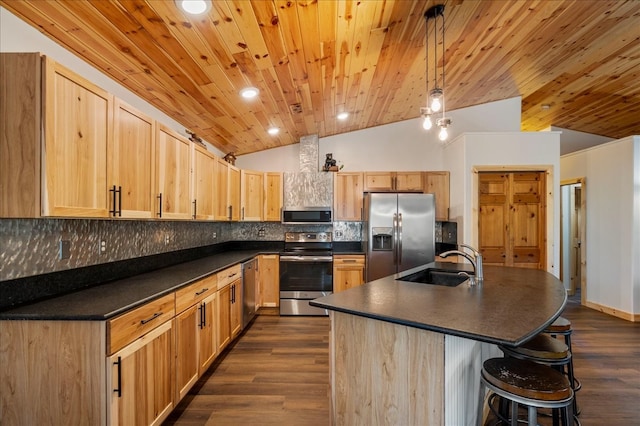 kitchen featuring stainless steel appliances, lofted ceiling, a center island with sink, dark hardwood / wood-style flooring, and sink