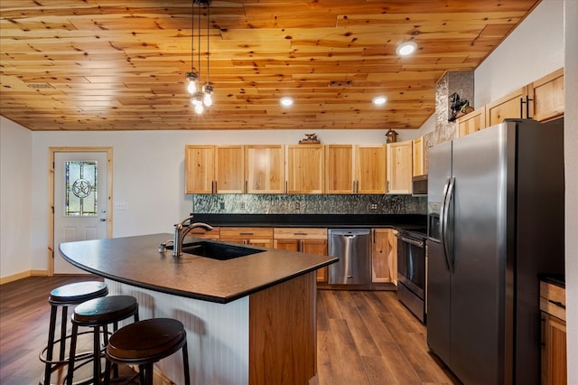 kitchen with dark hardwood / wood-style flooring, sink, a kitchen island with sink, and appliances with stainless steel finishes