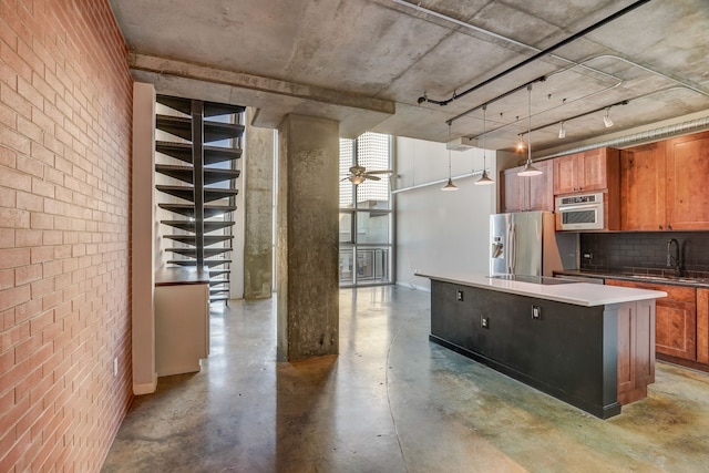 kitchen with appliances with stainless steel finishes, decorative light fixtures, sink, ceiling fan, and a center island