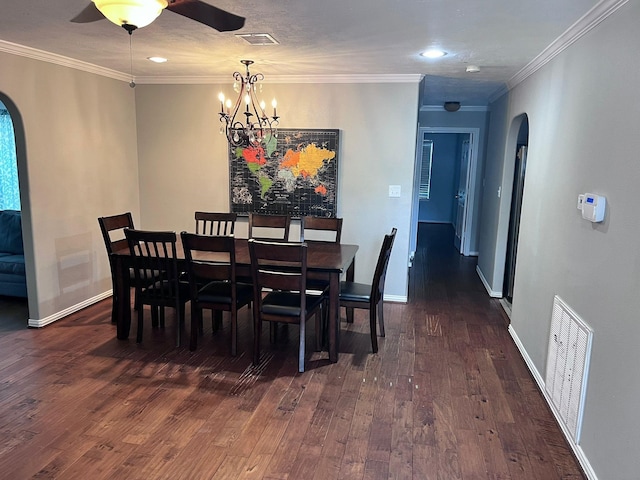 dining room with dark wood-type flooring, ceiling fan with notable chandelier, and crown molding