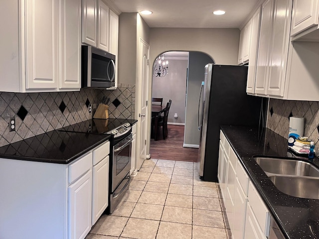 kitchen with tasteful backsplash, white cabinets, light tile patterned floors, and stainless steel appliances