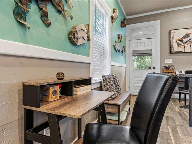 office with light wood-type flooring, wooden walls, and crown molding