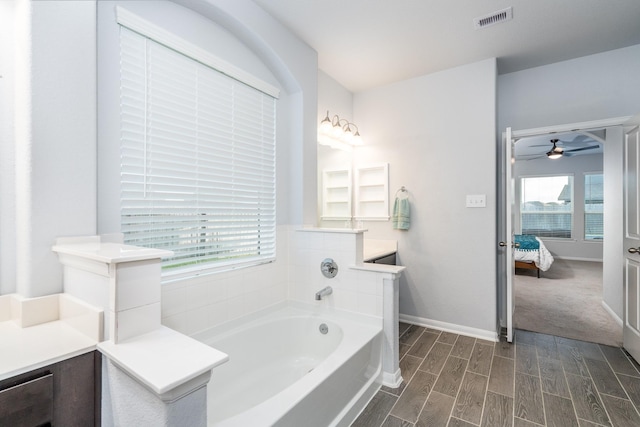 bathroom featuring ceiling fan, a washtub, and vanity