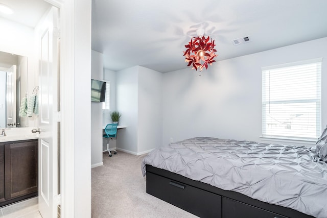 bedroom with multiple windows, ensuite bathroom, and light colored carpet