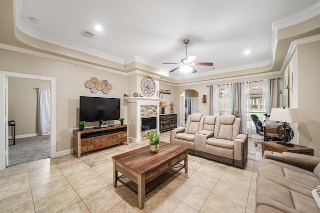 tiled living room with a fireplace, a tray ceiling, ceiling fan, and ornamental molding