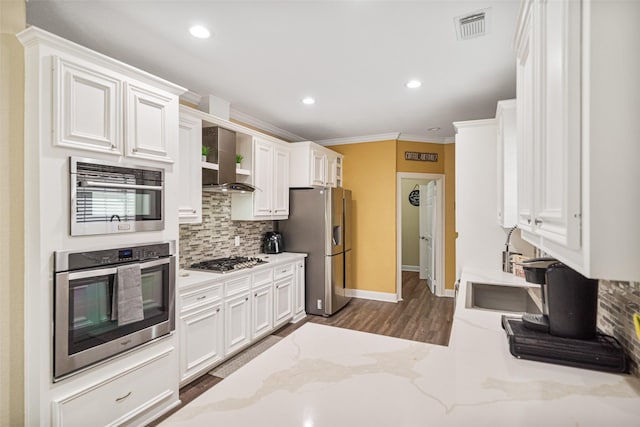 kitchen with stainless steel appliances, wall chimney range hood, light stone counters, backsplash, and white cabinets