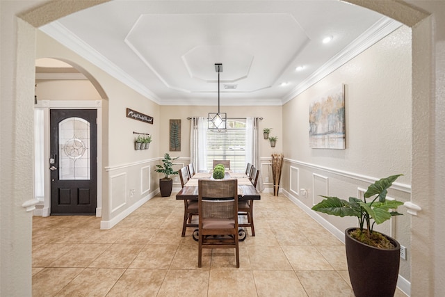 tiled dining space featuring a raised ceiling and crown molding