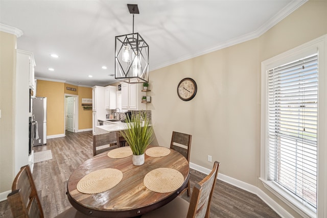 dining space with a chandelier, crown molding, sink, and dark wood-type flooring