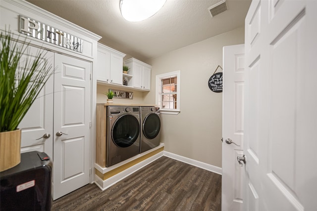 clothes washing area with a textured ceiling, cabinets, independent washer and dryer, and dark wood-type flooring