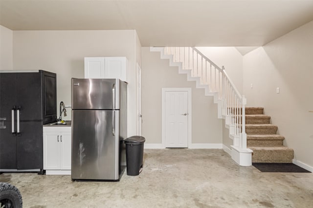 kitchen with white cabinets, black fridge, sink, and stainless steel refrigerator