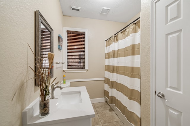 bathroom with tile patterned floors, vanity, and a textured ceiling