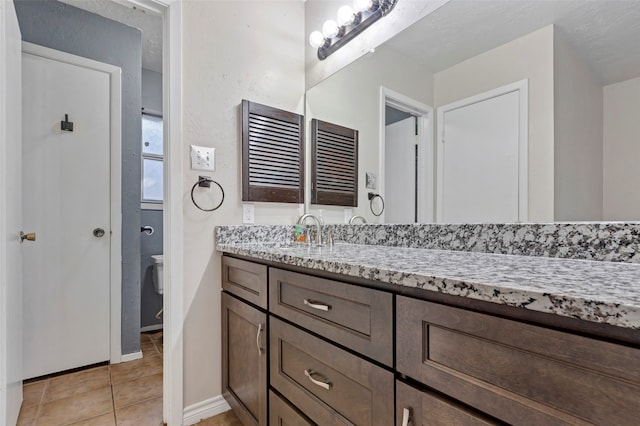 bathroom with tile patterned flooring, vanity, and toilet