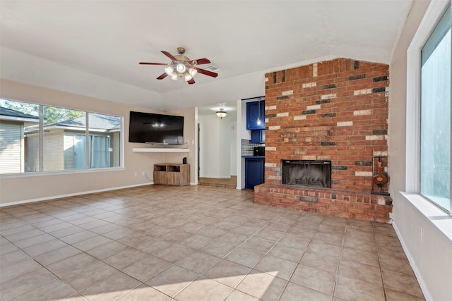 unfurnished living room with a brick fireplace, ceiling fan, light tile patterned floors, and vaulted ceiling