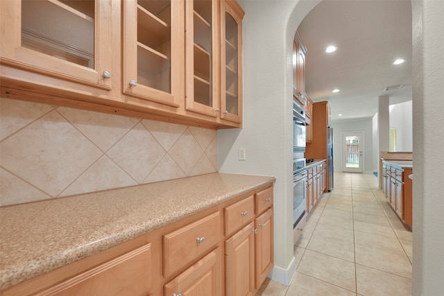 kitchen with stainless steel appliances, light tile patterned floors, backsplash, and light brown cabinets