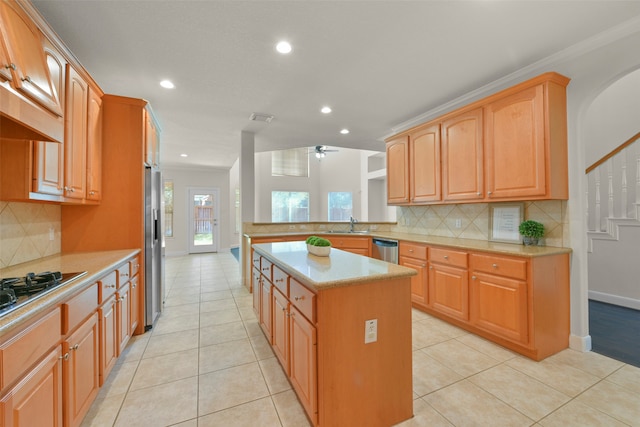 kitchen with stainless steel appliances, a center island, light tile patterned floors, tasteful backsplash, and crown molding