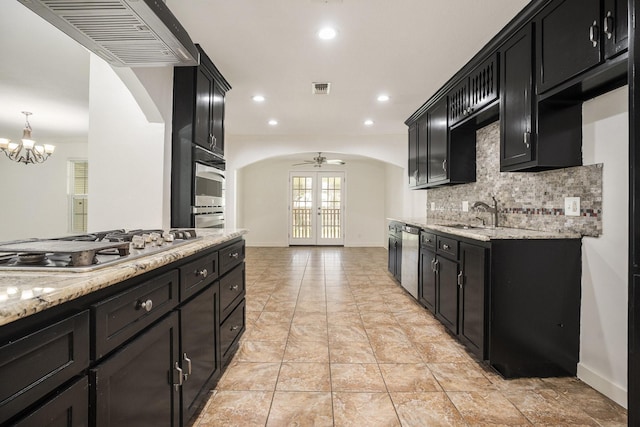 kitchen with french doors, sink, stainless steel appliances, decorative light fixtures, and ceiling fan with notable chandelier