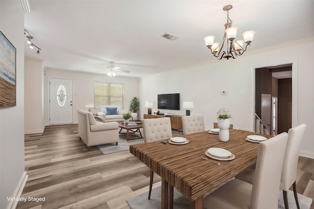 dining area with ceiling fan with notable chandelier, light wood-type flooring, and ornamental molding