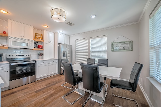 dining room with light hardwood / wood-style floors, a healthy amount of sunlight, and ornamental molding