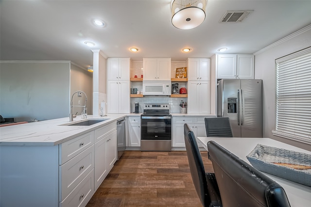 kitchen featuring white cabinets, appliances with stainless steel finishes, dark wood-type flooring, and ornamental molding