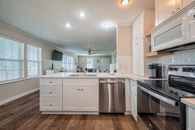 kitchen with stainless steel appliances, white cabinets, dark wood-type flooring, and kitchen peninsula