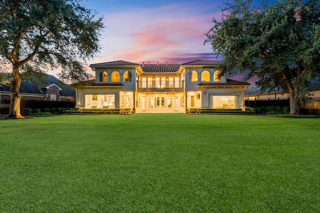 back house at dusk with a lawn