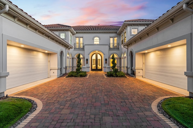 view of front of property with a balcony, french doors, and a garage