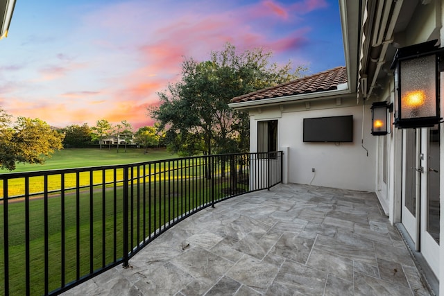 balcony at dusk featuring a patio