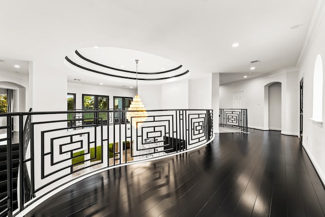 corridor with an inviting chandelier, a tray ceiling, hardwood / wood-style floors, and crown molding