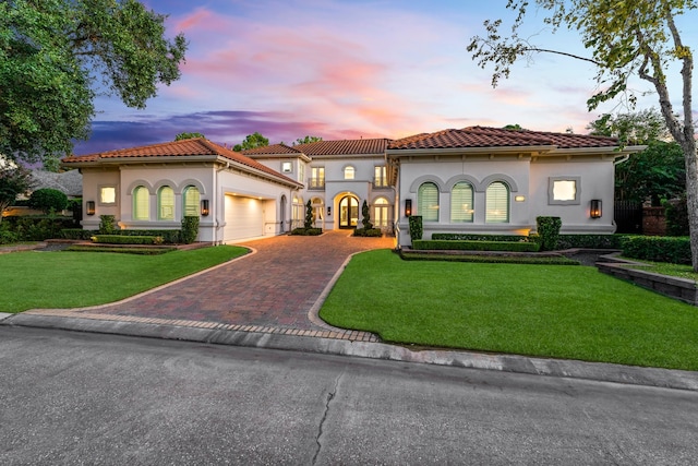 mediterranean / spanish-style home featuring a garage and a yard