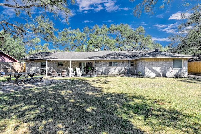 rear view of property featuring a lawn and a patio area