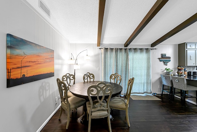 dining space featuring beamed ceiling, a textured ceiling, and dark wood-type flooring