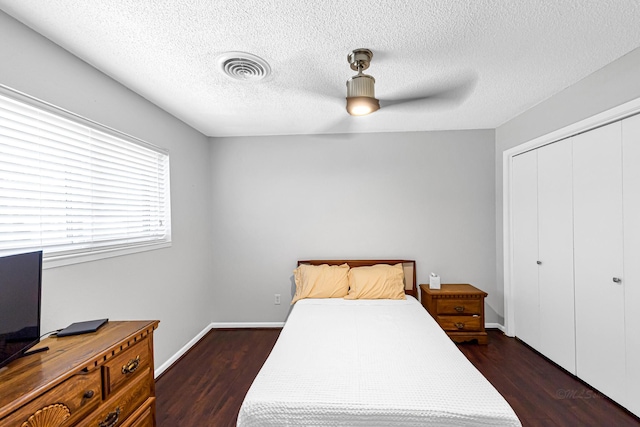 bedroom with a textured ceiling, a closet, dark hardwood / wood-style floors, and ceiling fan