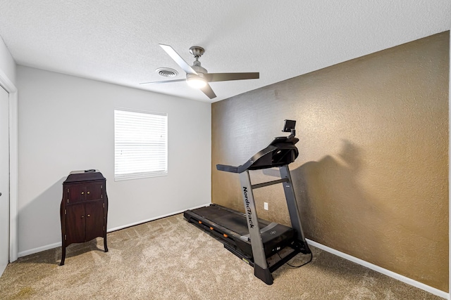 workout room featuring carpet, ceiling fan, and a textured ceiling