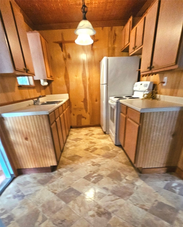 kitchen featuring hanging light fixtures, wooden walls, white electric range oven, and sink