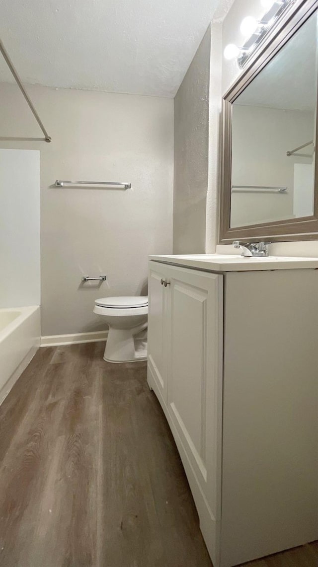 full bathroom featuring hardwood / wood-style floors, vanity, toilet, and shower / bathing tub combination