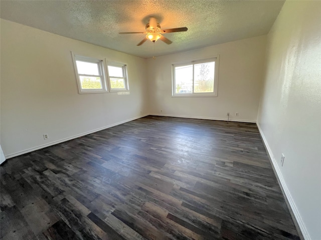 empty room with a textured ceiling, dark wood-type flooring, a healthy amount of sunlight, and ceiling fan